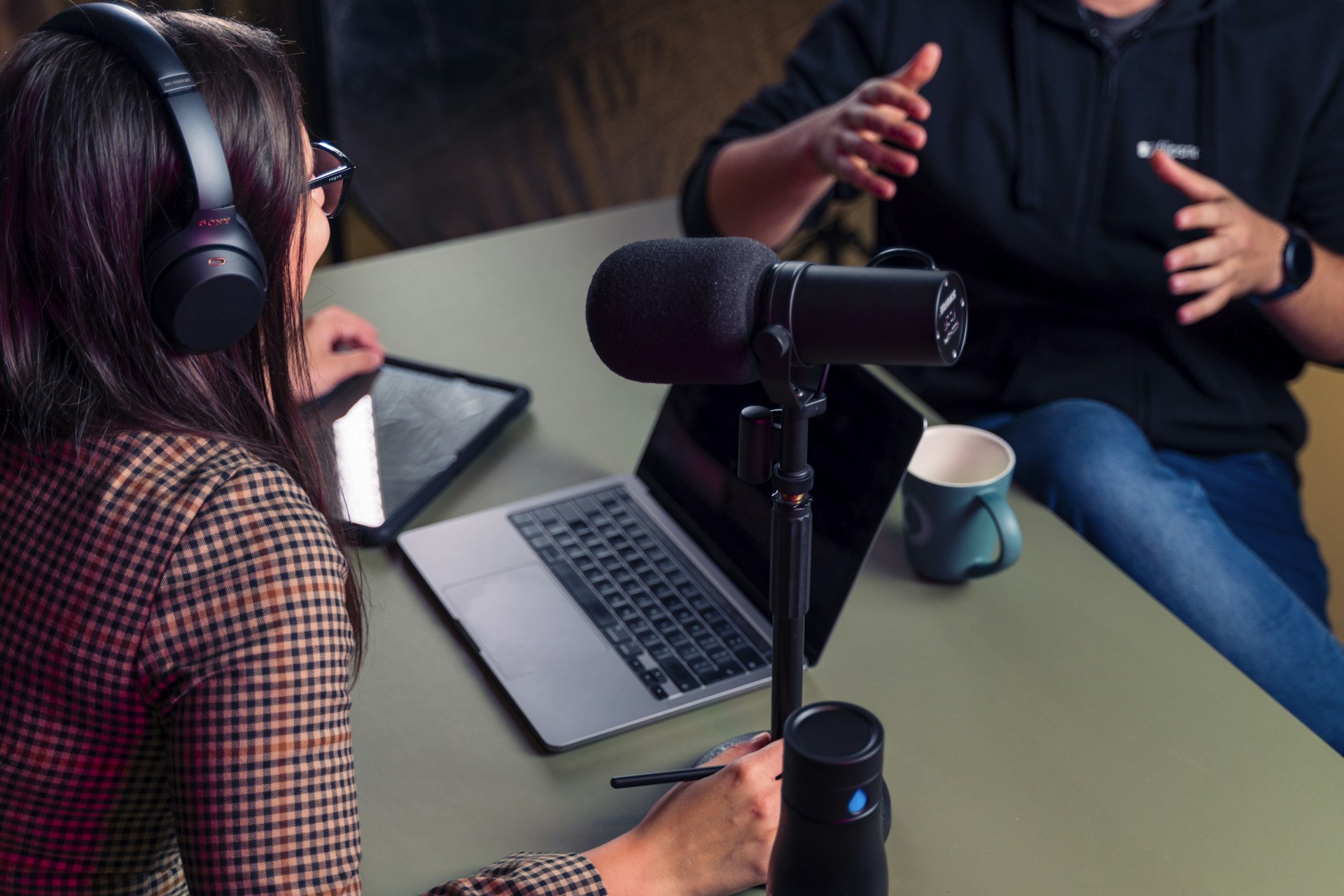 Person with headphones working at a laptop in a home studio setup