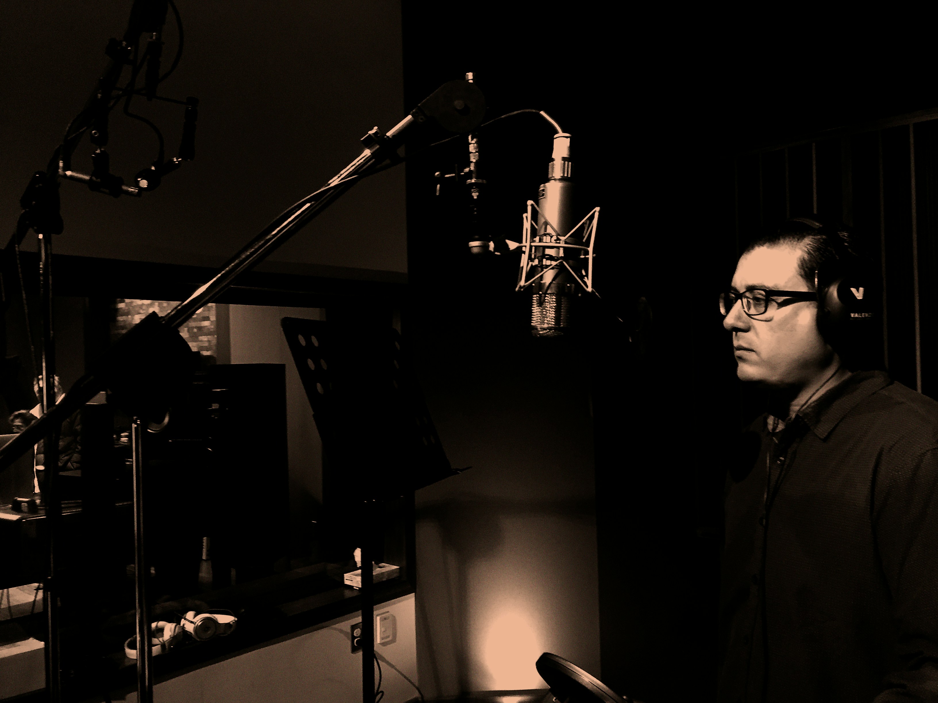 Man standing in front of condenser microphone in recording studio