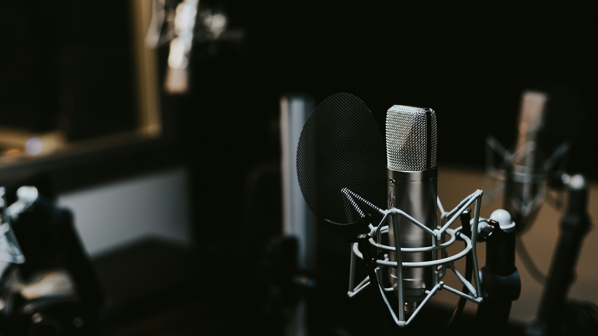 Black Rode condenser microphone beside computer monitor in studio setup
