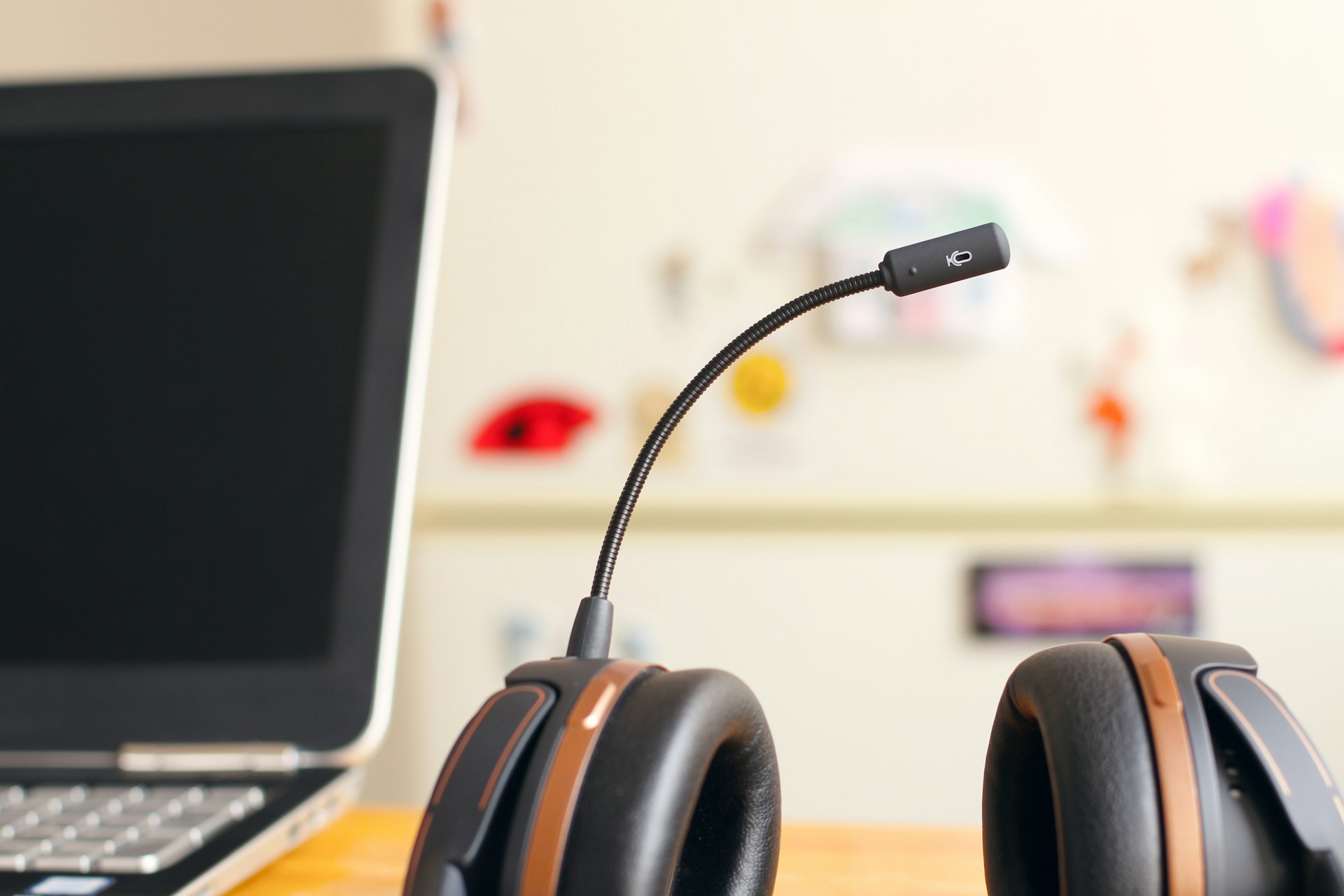 Black and brown headset near laptop computer on white desk
