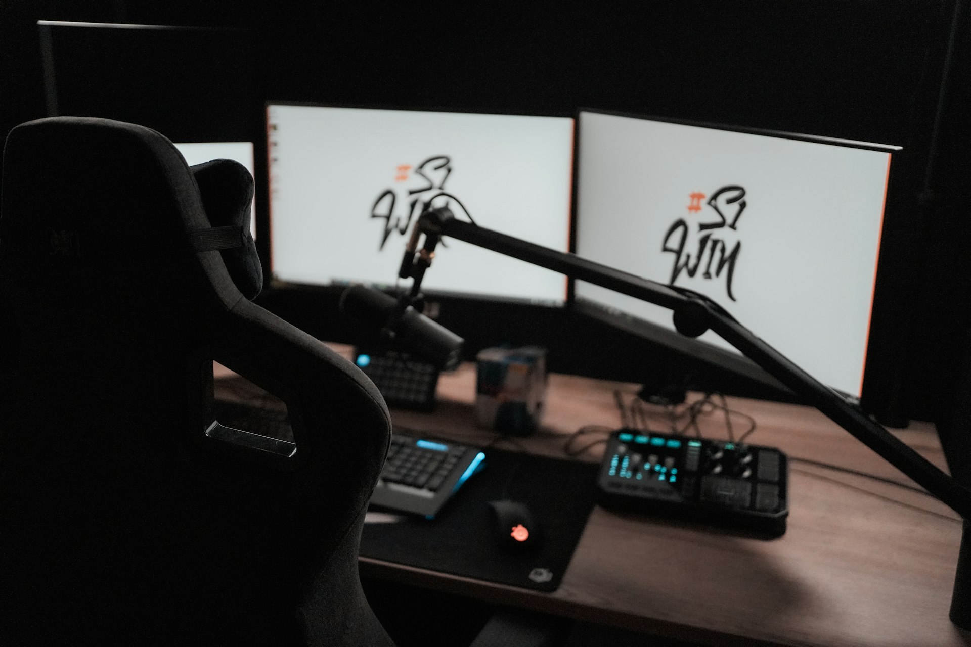 Gaming desk with two monitors and microphone setup at night